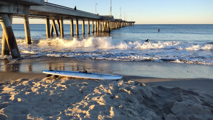 surf board on beach by pier