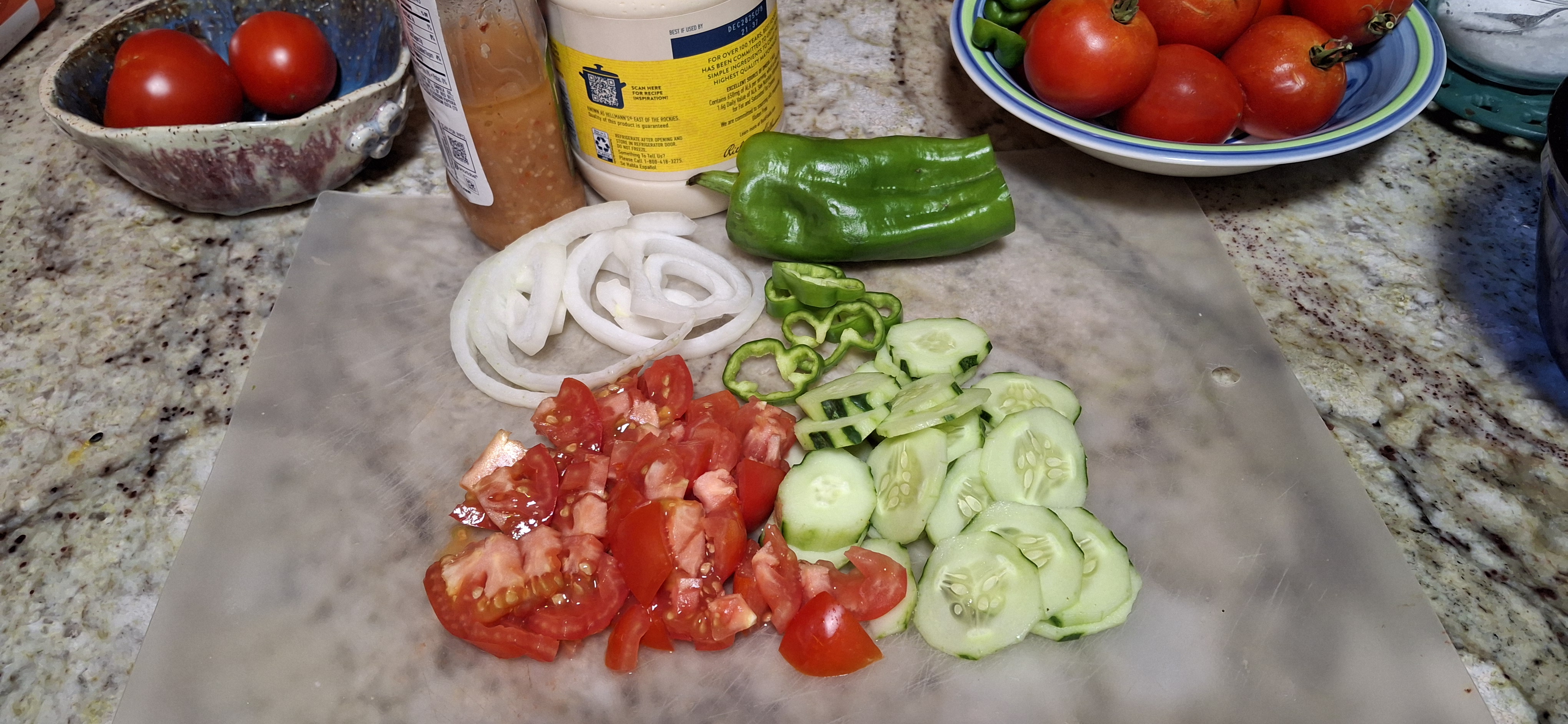 tomatoes, cucumbers, onions and green pepper chopped on a cutting board