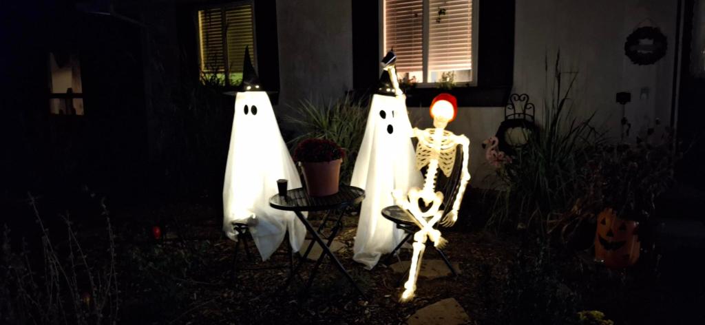 Skeleton and two ghosts lit up at night in yard